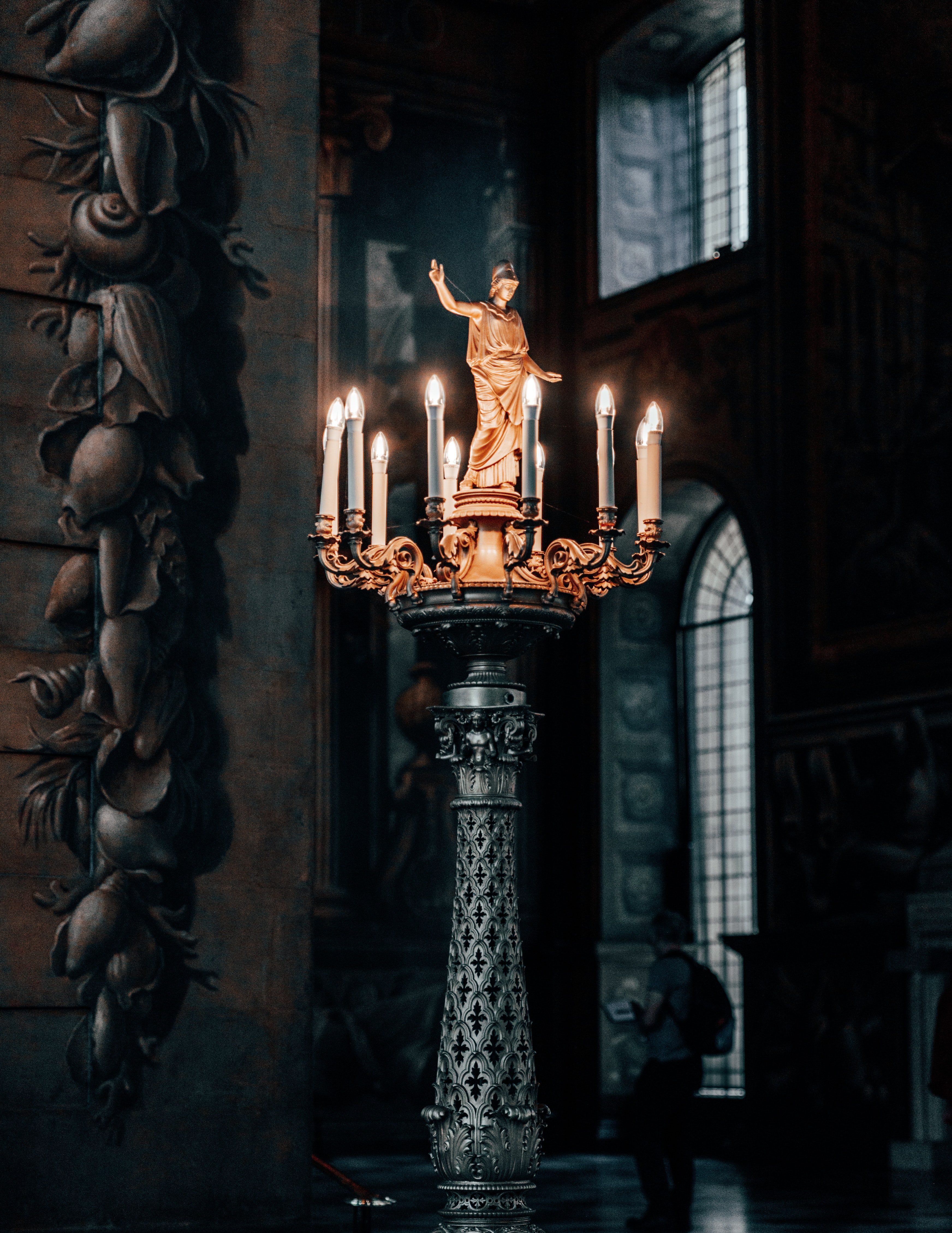 old church candles on candelabra with a saint statue on top
